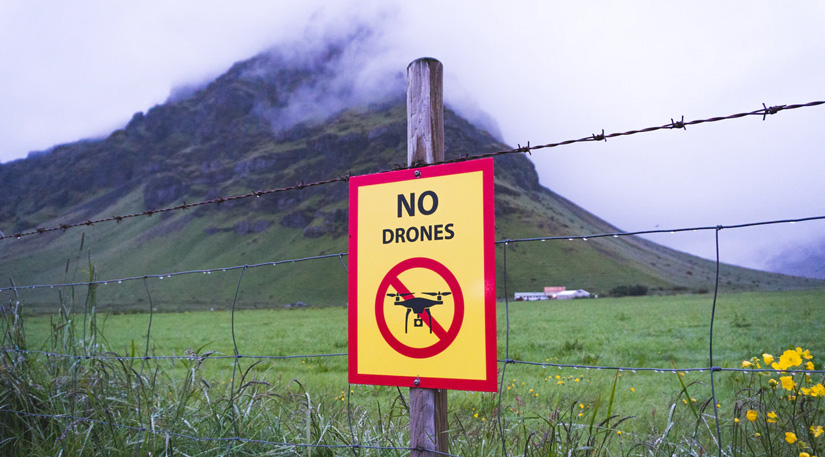 A 'no drones permitted' sign in front of a mountain