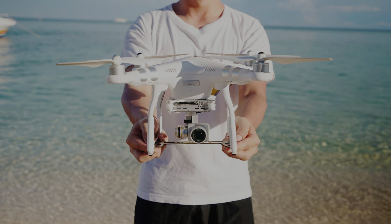 A man holding a drone on the beach