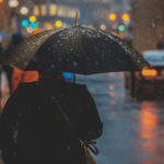 A person in a rainy street with an umbrella